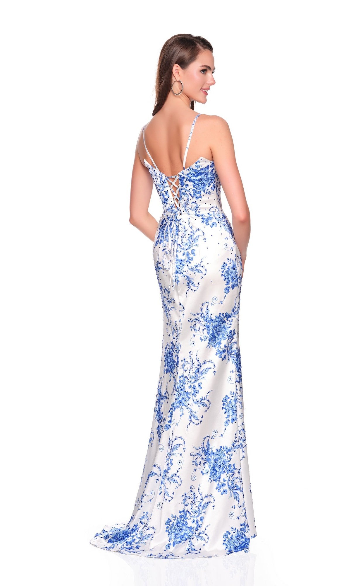 A woman wears the Long Prom Dress: Dave and Johnny 12940, a floor-length blue fitted gown with thin straps, lace-up open back, low cut, and delicate blue floral patterns for an elegant look.